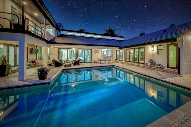 pool at twilight featuring outdoor lounge area and a patio