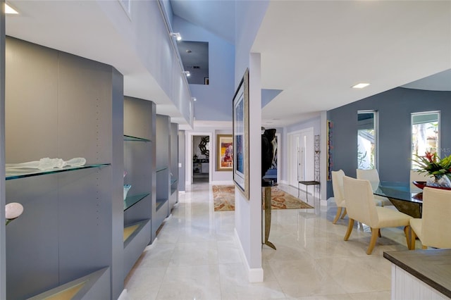 hallway with light tile floors and a towering ceiling