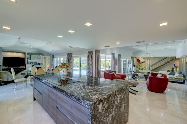 kitchen featuring a kitchen island, dark stone countertops, light tile floors, and lofted ceiling