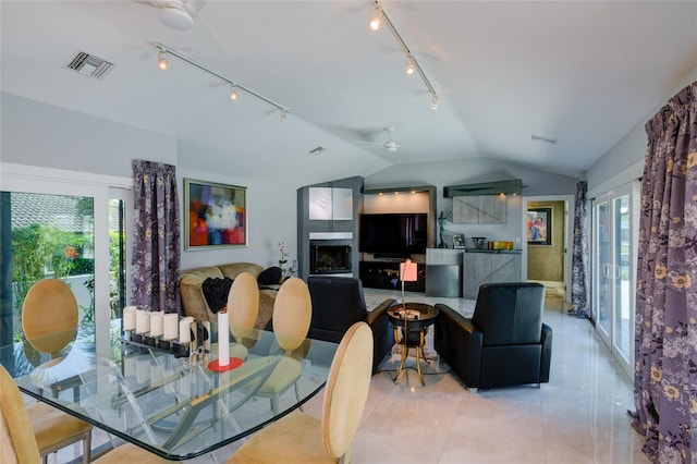 tiled dining space featuring plenty of natural light, rail lighting, ceiling fan, and vaulted ceiling