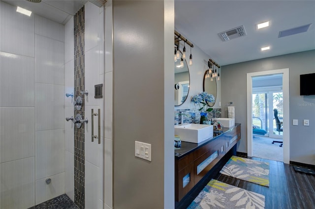 bathroom featuring dual bowl vanity and a shower with shower door