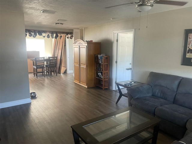 living room with a textured ceiling, ceiling fan, and dark hardwood / wood-style floors