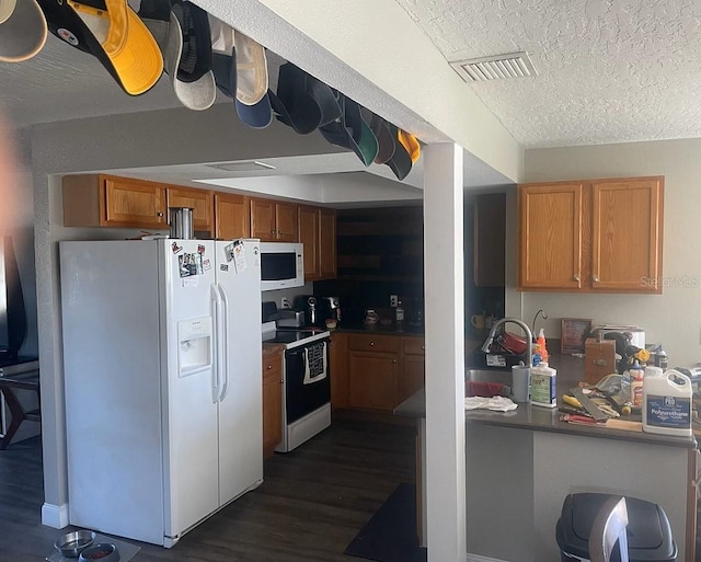 kitchen with a textured ceiling, white appliances, dark hardwood / wood-style floors, and sink