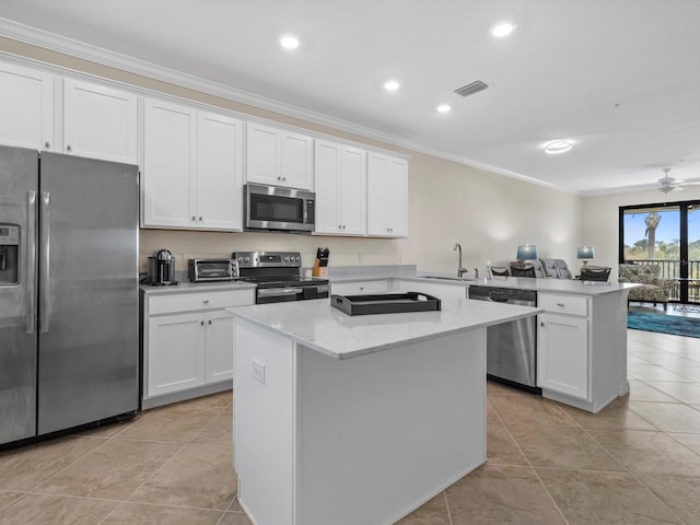 kitchen featuring light tile floors, a kitchen island, ceiling fan, appliances with stainless steel finishes, and crown molding