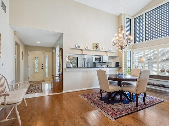 dining space with light tile floors, a notable chandelier, and high vaulted ceiling