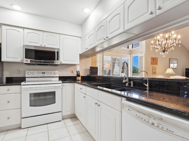 kitchen with white appliances, sink, light tile floors, white cabinets, and a chandelier