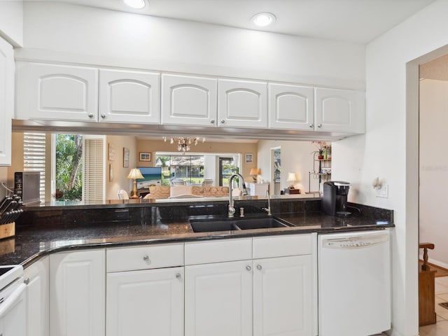 kitchen featuring dark stone countertops, white appliances, white cabinetry, and sink