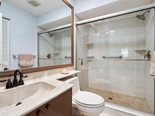 bathroom featuring toilet, vanity with extensive cabinet space, and an enclosed shower