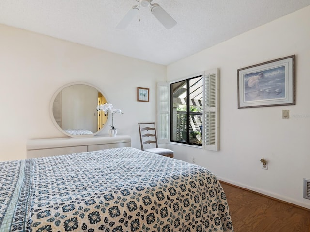 bedroom with ceiling fan, a textured ceiling, and dark wood-type flooring