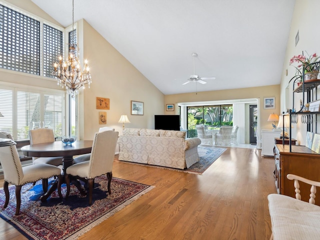 dining room featuring high vaulted ceiling, ceiling fan with notable chandelier, and light wood-type flooring