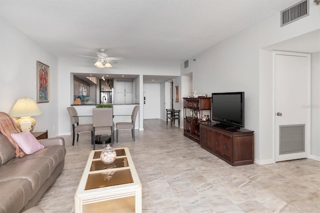 living room featuring light tile floors, a textured ceiling, and ceiling fan