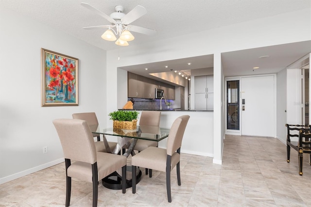 tiled dining space with ceiling fan and a textured ceiling