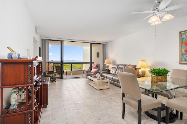 living room featuring light tile flooring, a wall of windows, and ceiling fan