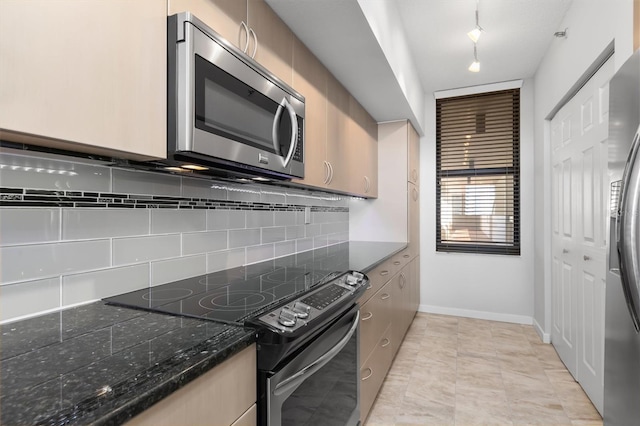 kitchen with tasteful backsplash, appliances with stainless steel finishes, light tile floors, and dark stone countertops