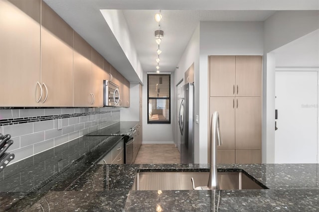 kitchen featuring light brown cabinets, stainless steel appliances, tasteful backsplash, dark stone countertops, and sink