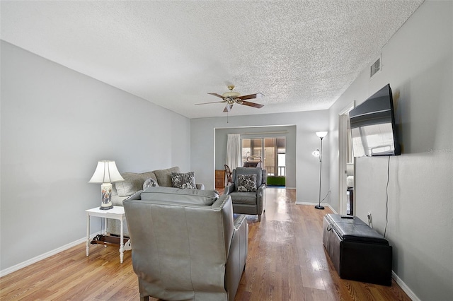 living room featuring ceiling fan, a textured ceiling, and light wood-type flooring