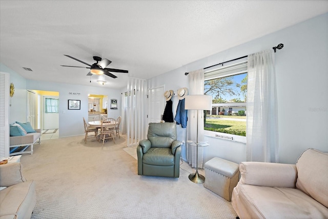 living area featuring light carpet and ceiling fan