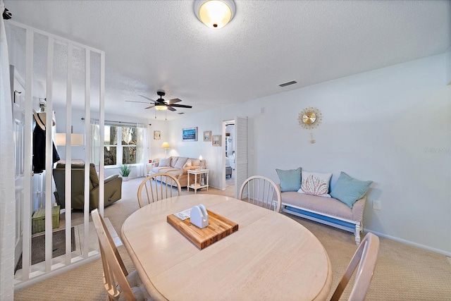 dining space with light carpet, a textured ceiling, and ceiling fan