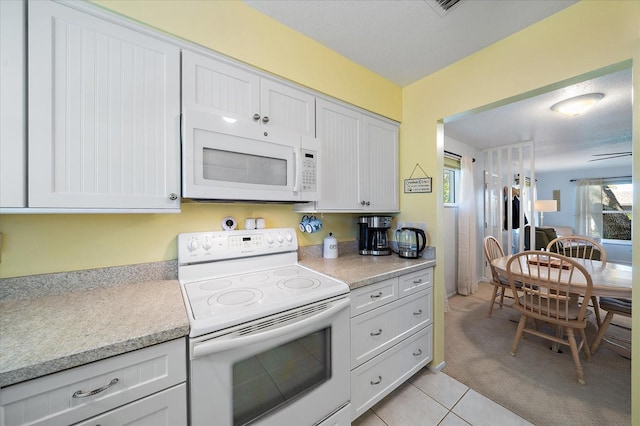 kitchen featuring white appliances, white cabinets, a healthy amount of sunlight, and light tile floors