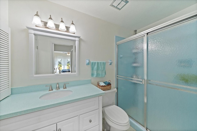 bathroom featuring a textured ceiling, toilet, large vanity, and a shower with door