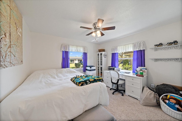 bedroom with ceiling fan, a textured ceiling, light colored carpet, and multiple windows