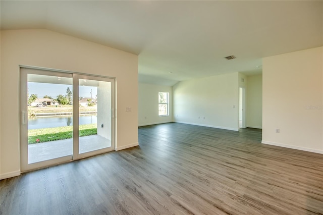 empty room featuring vaulted ceiling, a water view, and wood-type flooring