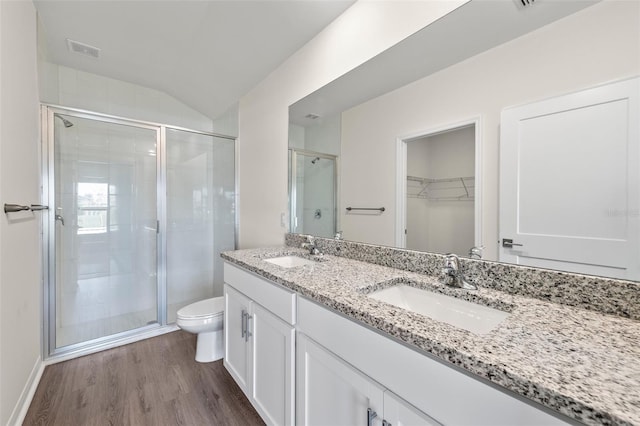 bathroom featuring toilet, wood-type flooring, walk in shower, vanity, and vaulted ceiling