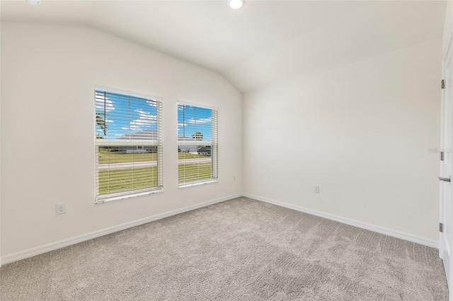 carpeted spare room with vaulted ceiling