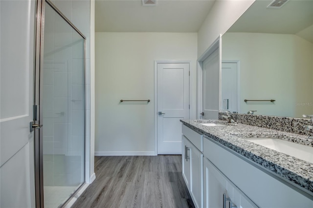 bathroom featuring an enclosed shower, wood-type flooring, and dual bowl vanity