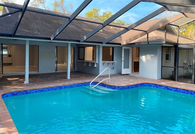 view of swimming pool featuring glass enclosure and a patio area