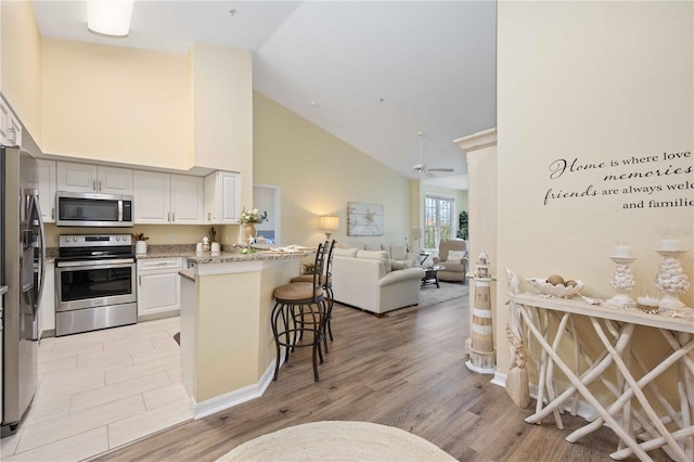 kitchen featuring kitchen peninsula, a breakfast bar, stainless steel appliances, and light wood-type flooring