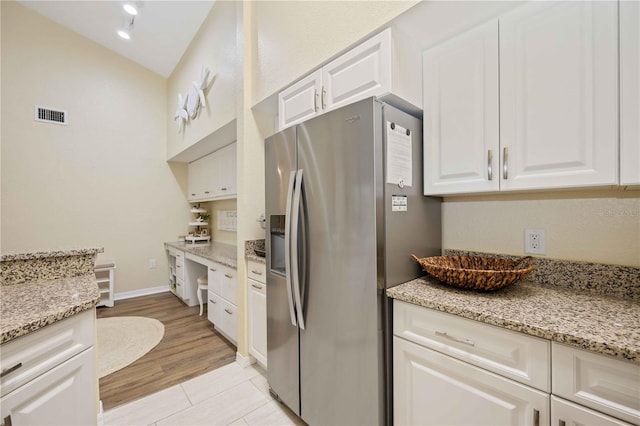 kitchen featuring white cabinetry, stainless steel fridge with ice dispenser, light stone countertops, and light wood-type flooring