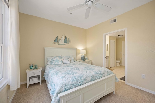 bedroom with ceiling fan, light carpet, and connected bathroom