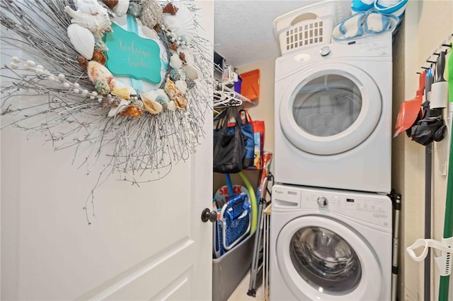 laundry area featuring stacked washer / drying machine and a textured ceiling