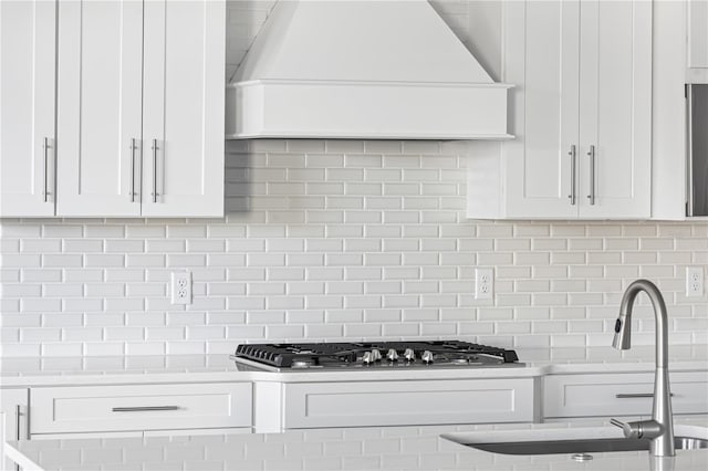 kitchen with premium range hood, tasteful backsplash, sink, and white cabinets