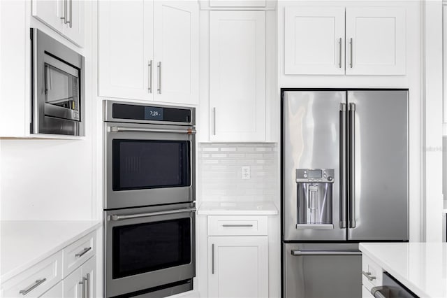 kitchen featuring decorative backsplash, stainless steel appliances, and white cabinetry