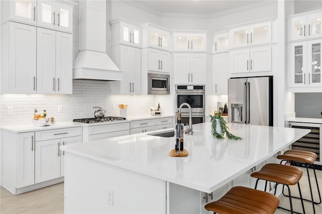 kitchen with white cabinets, custom exhaust hood, stainless steel appliances, and a breakfast bar