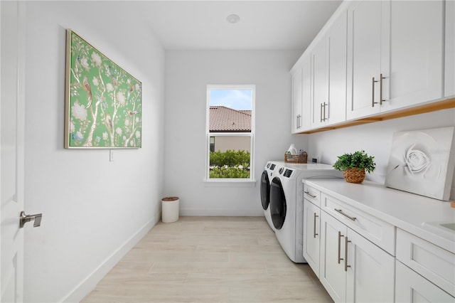 laundry room featuring cabinets, light hardwood / wood-style floors, and independent washer and dryer