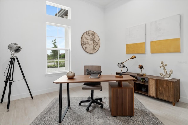 home office with light wood-type flooring and crown molding