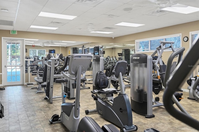 workout area featuring ceiling fan, a drop ceiling, and light tile floors