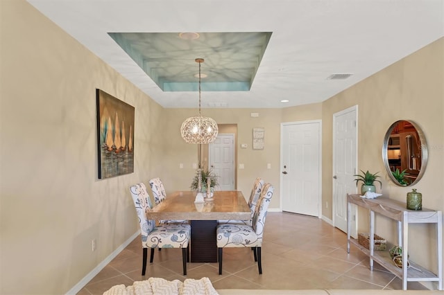 tiled dining area with a notable chandelier and a tray ceiling