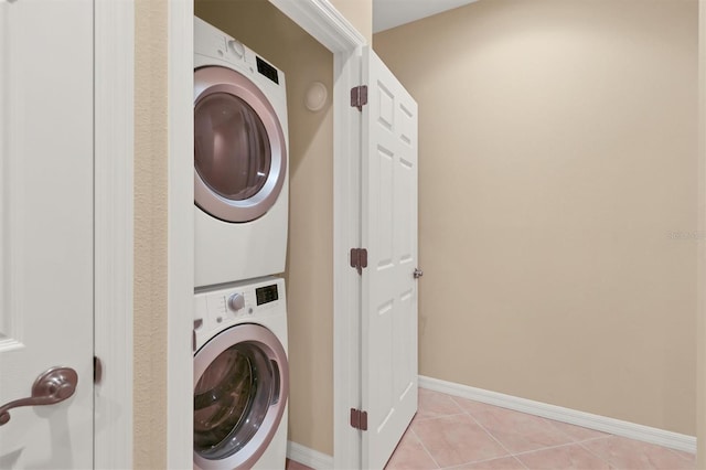 clothes washing area with light tile floors and stacked washing maching and dryer