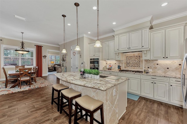 kitchen featuring hanging light fixtures, a kitchen island with sink, dark hardwood / wood-style floors, and light stone counters