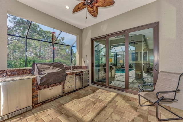 sunroom featuring sink, ceiling fan, and a wealth of natural light