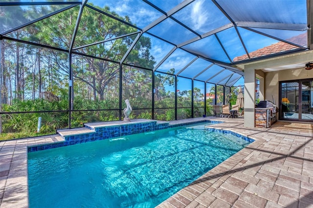 view of pool featuring a patio area, ceiling fan, pool water feature, and glass enclosure