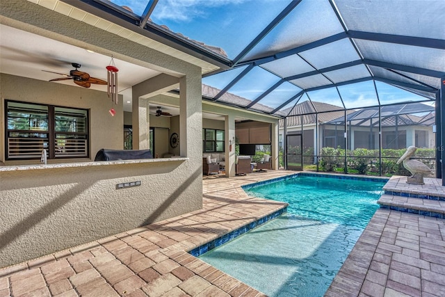 view of swimming pool featuring glass enclosure, ceiling fan, and a patio