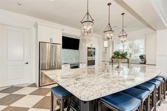 kitchen featuring stainless steel appliances, decorative light fixtures, and a kitchen breakfast bar