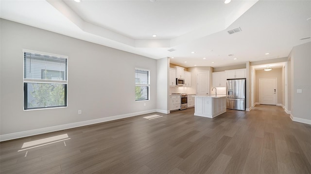 unfurnished living room featuring dark hardwood / wood-style flooring and a raised ceiling