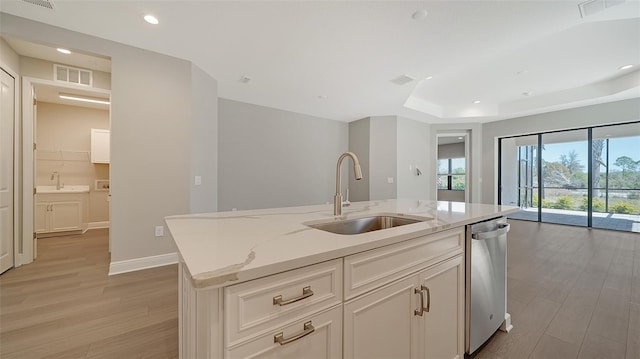 kitchen with plenty of natural light, sink, a kitchen island with sink, and light stone countertops