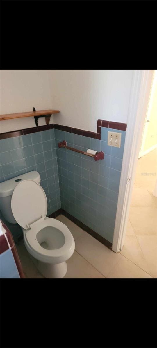 bathroom featuring tile flooring, toilet, and tile walls